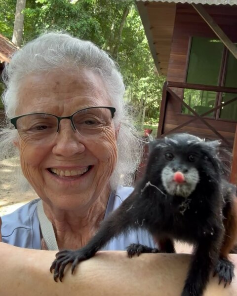 Isara smiling with a marmoset perched on her arm in Peru